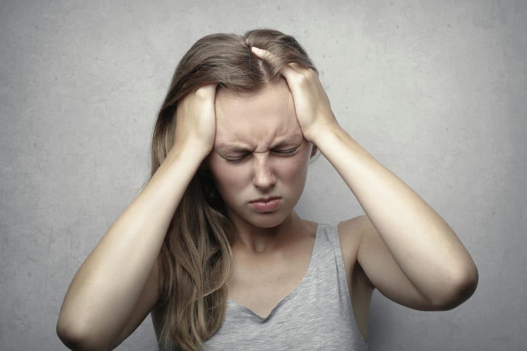 A woman sits with her head in her hands, conveying a sense of despair and frustration