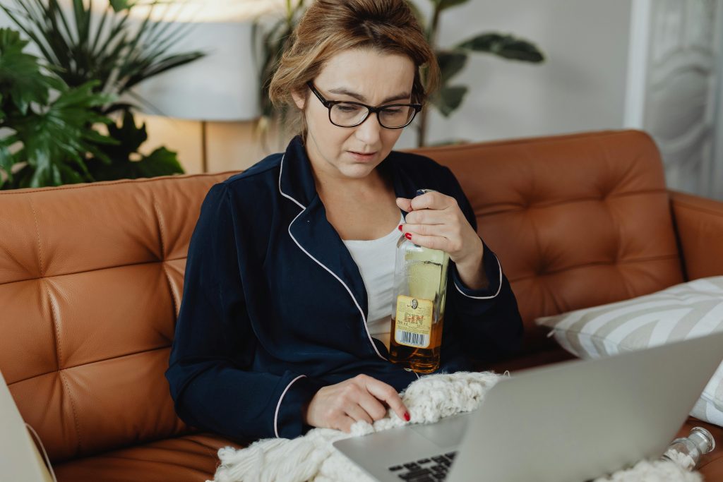 Woman struggling with alcohol addiction while working, highlighting the need for alcohol rehab treatment.